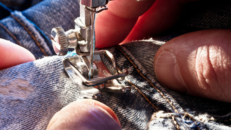 Nahaufnahme einer Nähmaschine bei der Reparatur einer Jeans